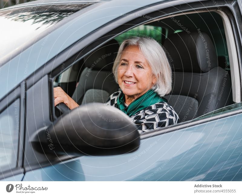 Aged female in elegant clothes driving car woman cheerful drive vehicle smile automobile senior classy happy aged pensioner sun driver positive outfit joy