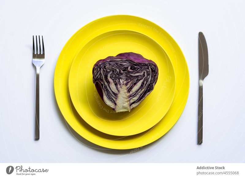 Yellows plates with cut red cabbage raw fresh healthy vegetable halved food vitamin ripe half fork knife stripe minimal delicious meal nutrition ingredient