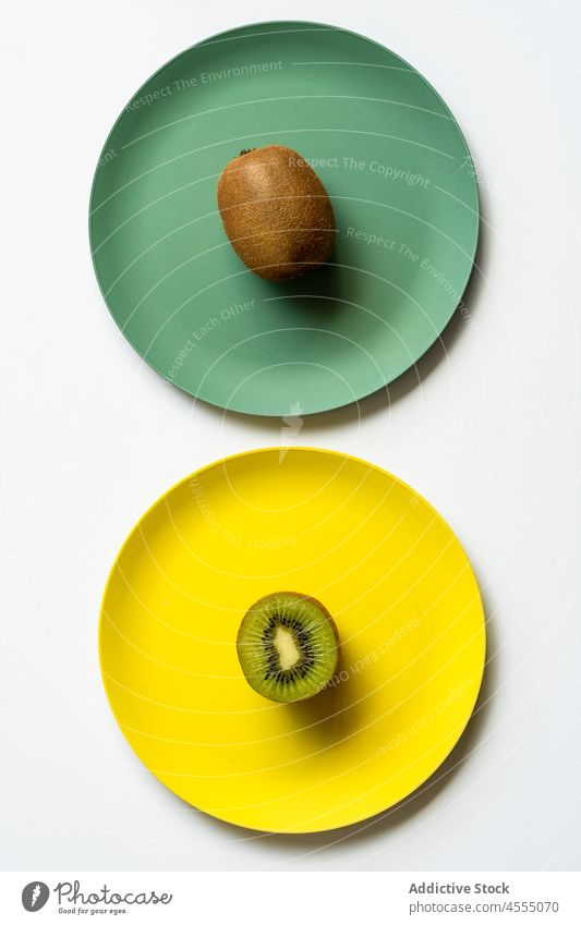 Whole and halved healthy kiwis served on plates fruit vitamin food ripe tasty whole meal raw ingredient appetizing fresh yellow green unpeeled table diet
