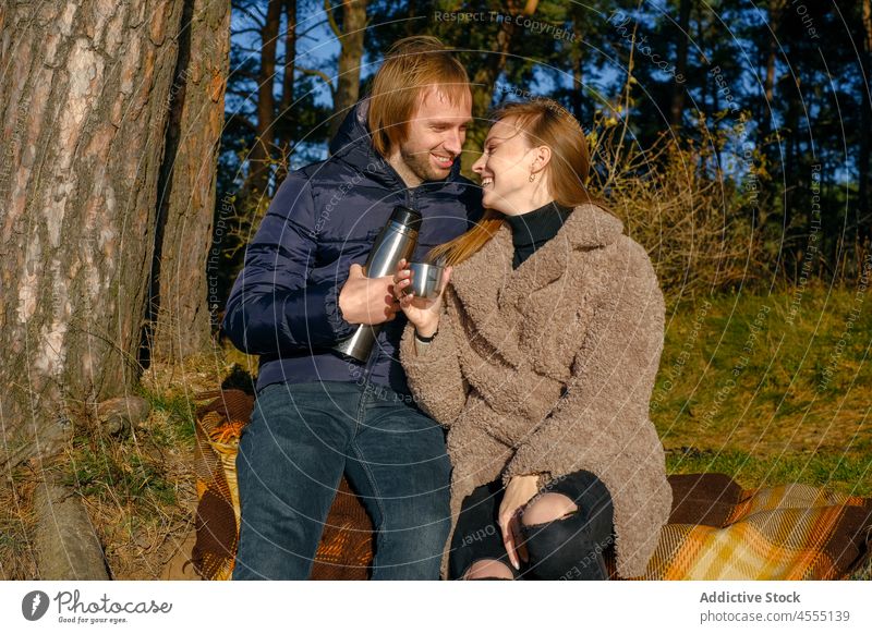 Content couple with thermos in nature romantic love relationship hot drink affection fondness pastime sweetheart date girlfriend boyfriend woman bonding tender