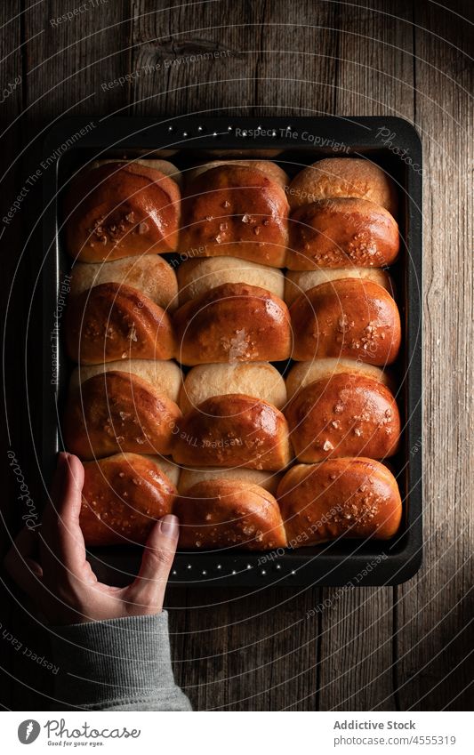 Crop baker with fresh rolls in tray cook soft dinner baked tasty delicious food bread baking pan chef row snack appetizing prepare palatable yummy nutrition