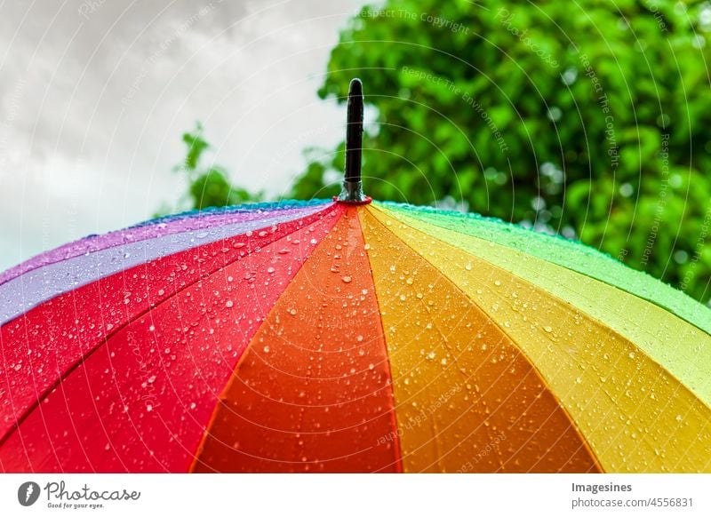 Rain on umbrella in rainbow colors under heavy rain against background of cloudy sky. Rainy weather concept. Umbrella Sky Autumn Bad Blue bokeh change Climate
