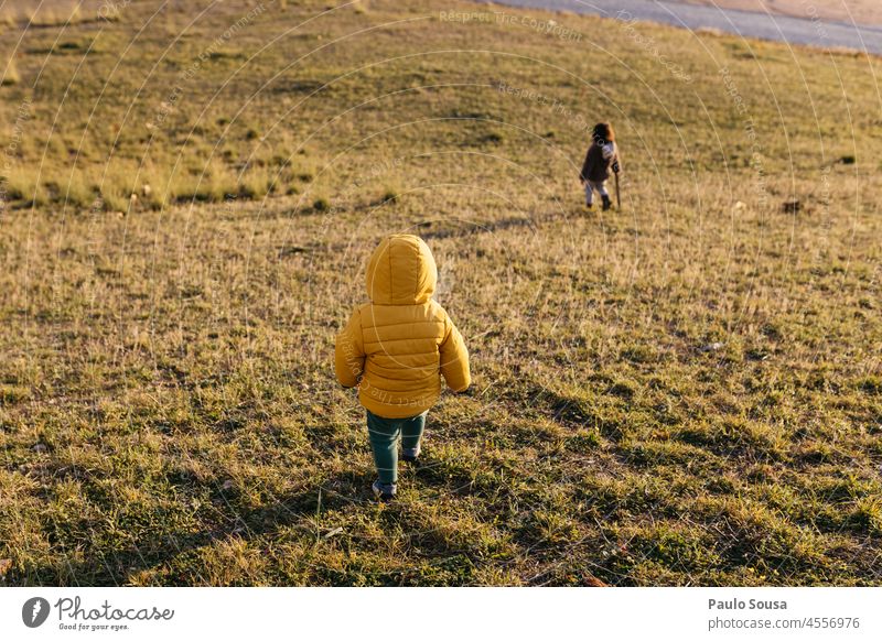 Rear view child walking Yellow Child childhood Brothers and sisters 1 - 3 years Grass Hooded (clothing) Hooded jacket Nature Autumn Leisure and hobbies