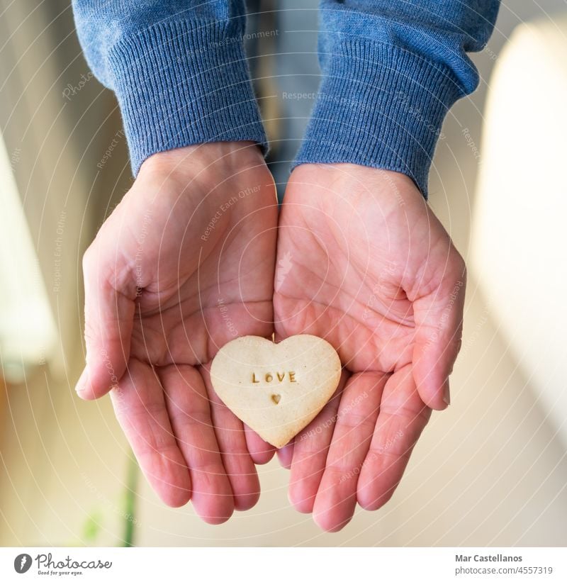 Hands with heart-shaped cookie. Letters LOVE. valentine give gift hands man love letters food heart shape in hands top view copy space fingers person