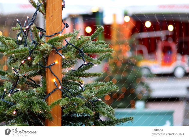 Fir tree with lights at Christmas market. Blurred background with a carousel car. Round bokeh. clearer fir tree Carousel Toy car Attraction bokeh lights twigs