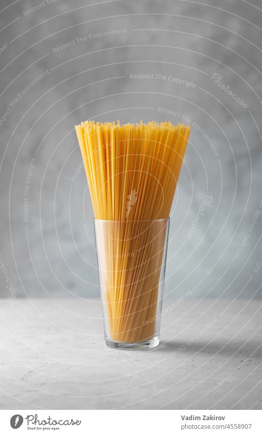 Raw spaghetti in a glass. Dry italian pasta prepared from durum wheat background yellow gray concrete view cooking traditional uncooked objects macaroni