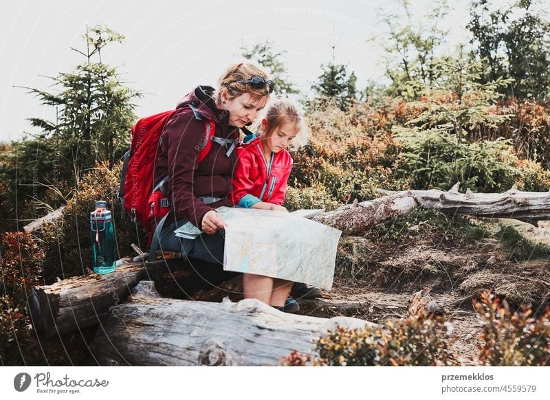 Family trip in mountains. Mother and her little daughter examining a map, sitting on stump during trip family child vacation summer hike travel journey active