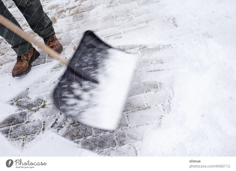 Snow shoveling - a man clears a paved driveway of fresh snow with a snow shovel / winter / motion blur Snow Shoveling Virgin snow Highway ramp (entrance)