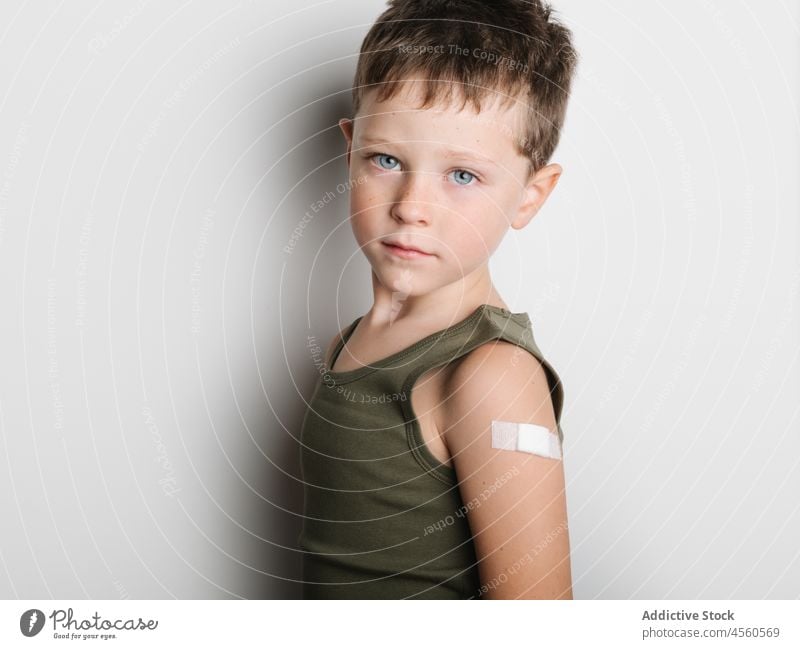 Schoolboy after vaccination with band aid on arm child vaccine cheerful jab serious kid shot injection healthy motivation childhood support medical epidemic