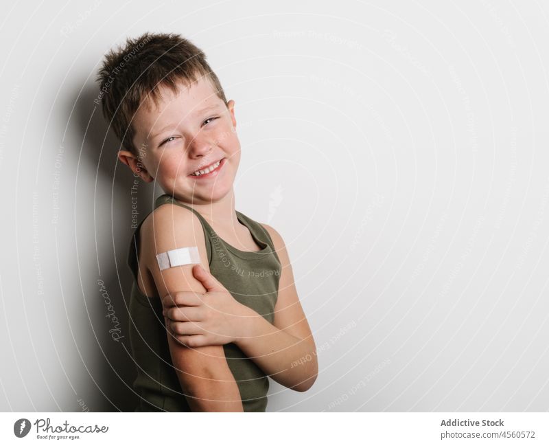 Cheerful schoolboy after vaccination with band aid on arm child vaccine cheerful jab kid shot injection healthy motivation childhood support medical epidemic
