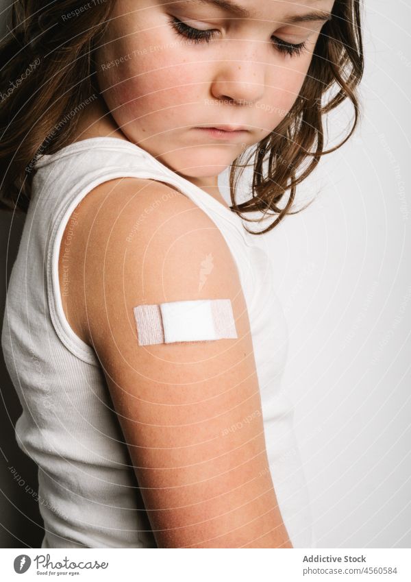 Serious vaccinated girl with band aid on arm schoolgirl bandage vaccine protect virus vaccination jab shot safety health care medical healthy serious prevent
