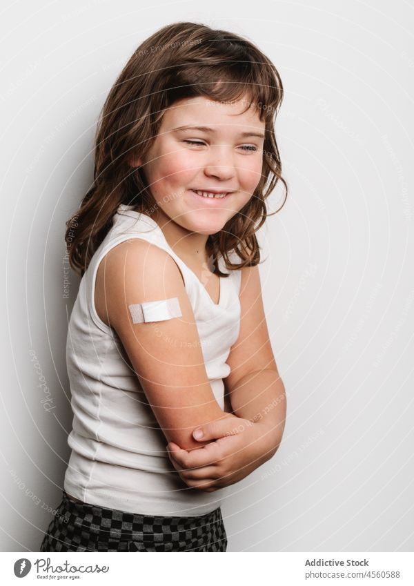 Happy vaccinated girl with band aid on arm schoolgirl bandage vaccine protect cheerful virus vaccination jab happy smile shot safety health care medical healthy
