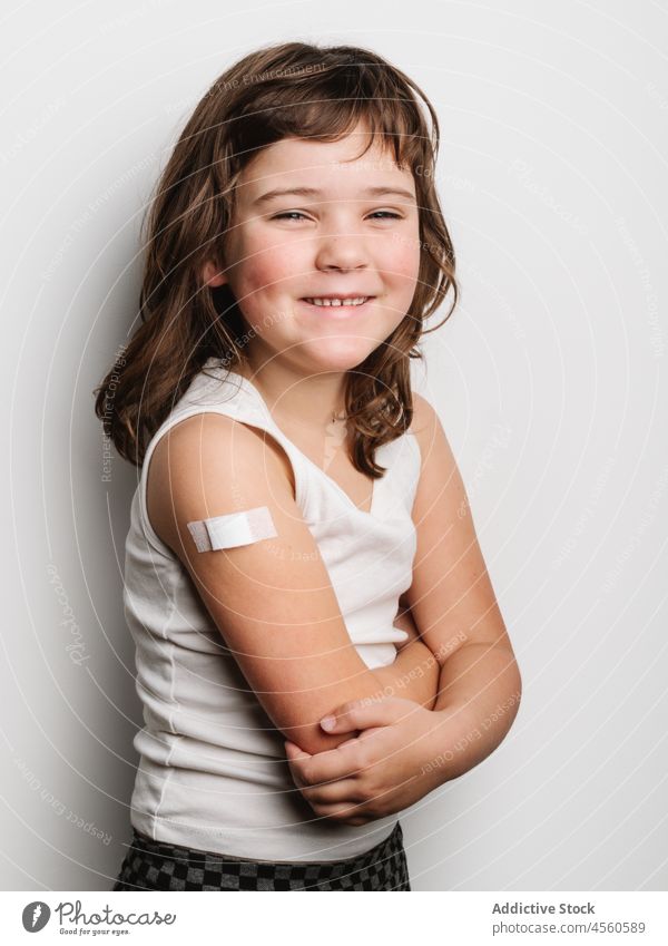 Happy vaccinated girl with band aid on arm schoolgirl bandage vaccine protect cheerful virus vaccination jab happy smile shot safety health care medical healthy