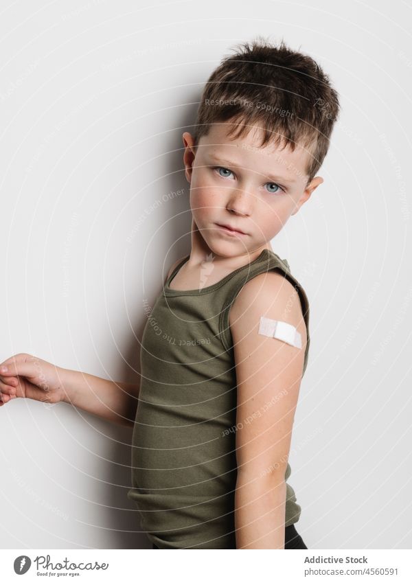 Schoolboy after vaccination with band aid on arm child vaccine cheerful jab serious kid shot injection healthy motivation childhood support medical epidemic