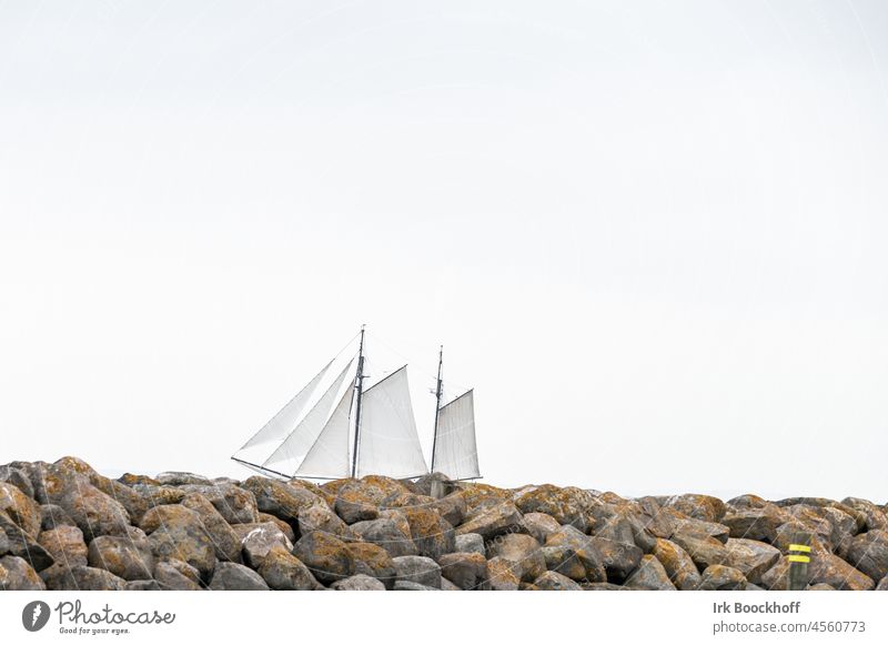 Sailing ship in front of stone wall and empty sky Copy Space black-white Subdued colour Sea coast Tourism travel bank endless seascape Relaxation peaceful...