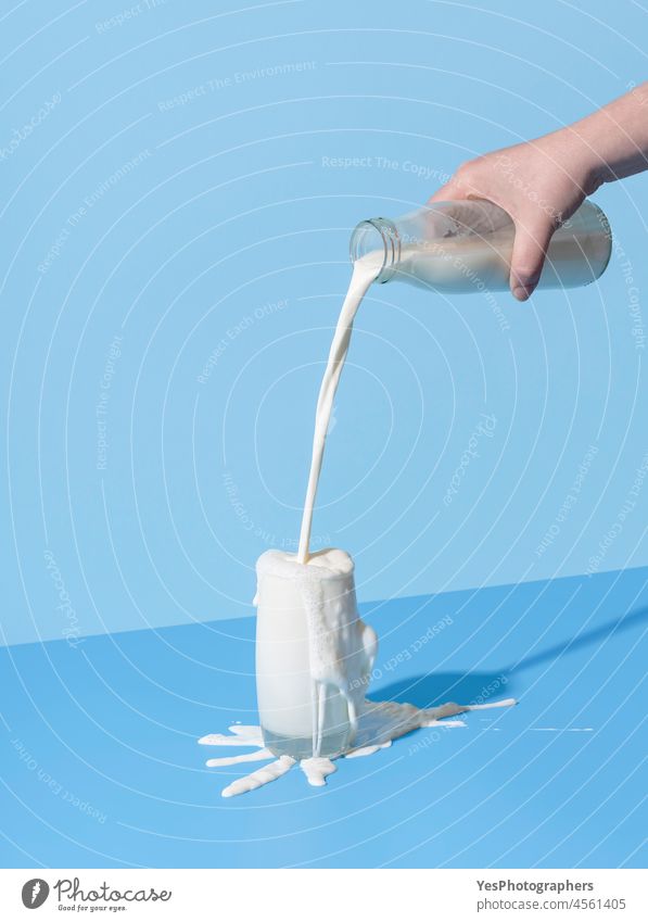 Pouring milk into the glass on a blue background. Spilled milk on the table. abstract advertising beverage bottle breakfast bright calcium clean color concept