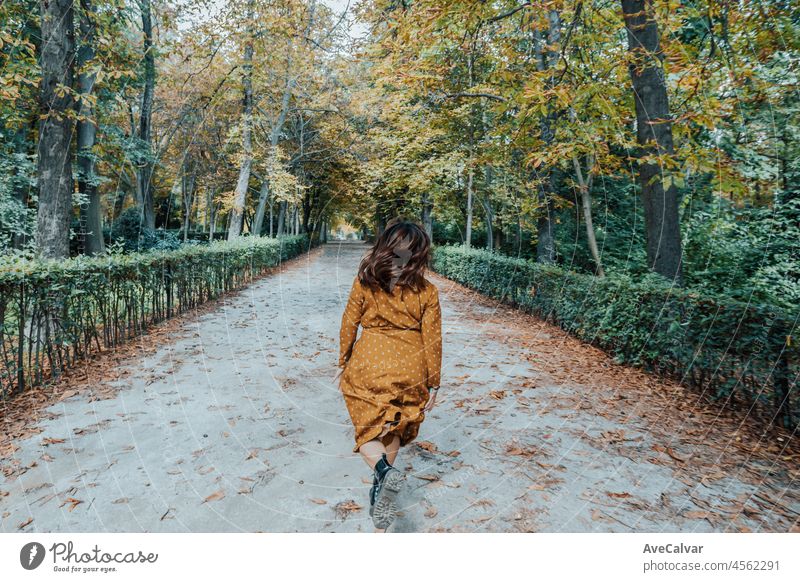 Woman running down a park route during peak of fall boho bohemian freedom hipster happy young portrait dress caucasian hairstyle lips look recreation outside