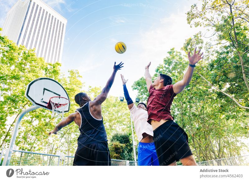 Group of friends jumping and tossing ball up men basketball play player game street sport positive man multiethnic cheerful throw happy sportsmen together