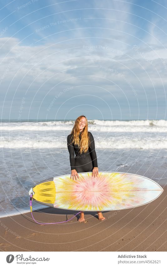 Woman with surfboard standing on wet beach woman coast shore smile hobby activity pastime sport sea water tide wave waterfront seaside nature seashore equipment