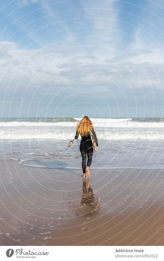 Woman with surfboard walking on wet beach woman coast shore hobby activity pastime sport sea water tide wave waterfront seaside nature seashore equipment summer