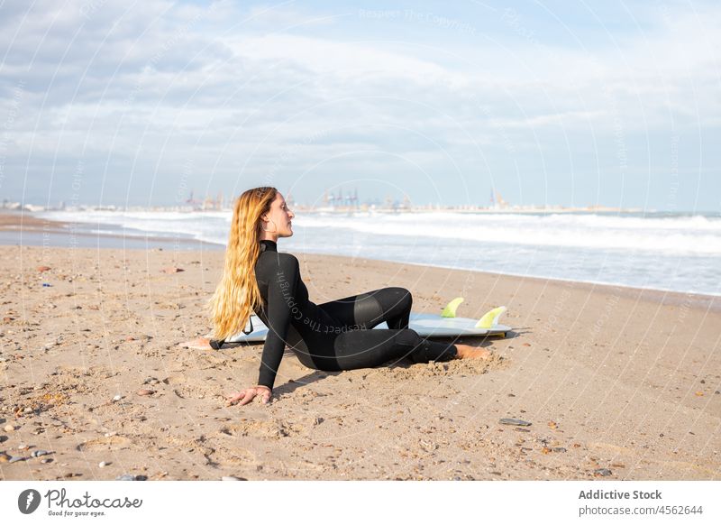 Young woman near surfboard on seashore coast hobby activity pastime sport water tide wave waterfront sand seaside nature equipment summer sunlight surfer female