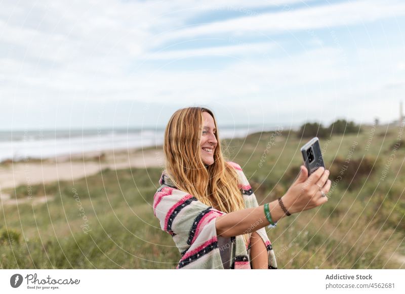 Cheerful woman taking selfie in nature smartphone self portrait capture photography pastime leisure recreation grass moment female lady smile mobile cheerful