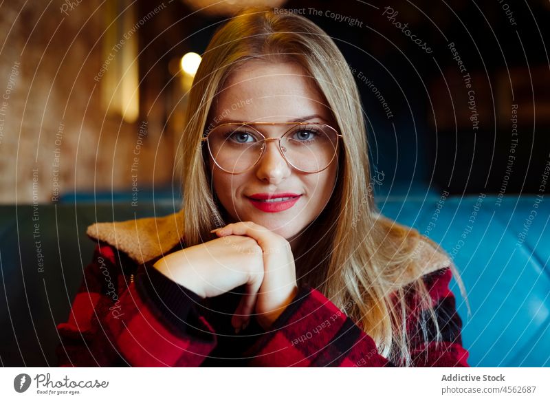 Young woman sitting on a coffee shop young portrait blonde calm casual smiling caucasian clothes colorful confident cute enjoy female glasses hands hipster