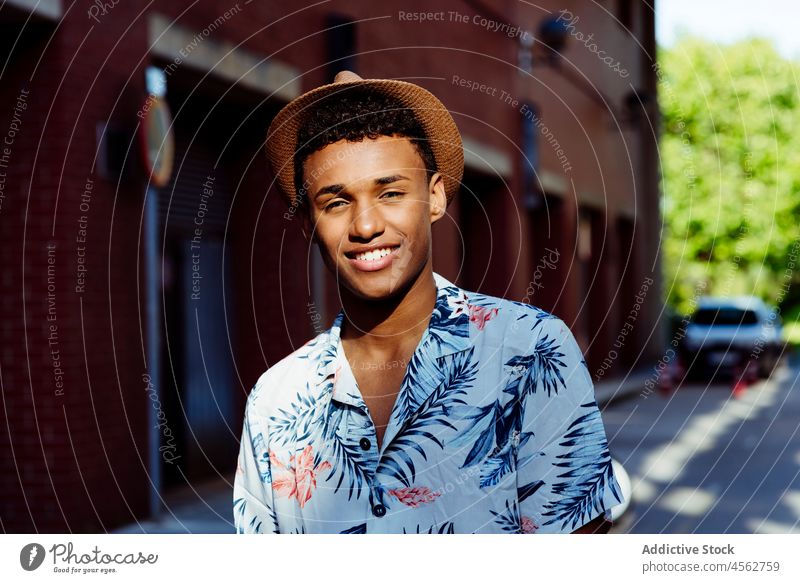 Trendy young black man portrait posing in the street male boy attractive handsome urban city laugh smile hat happy happiness fun summer summertime shirt floral
