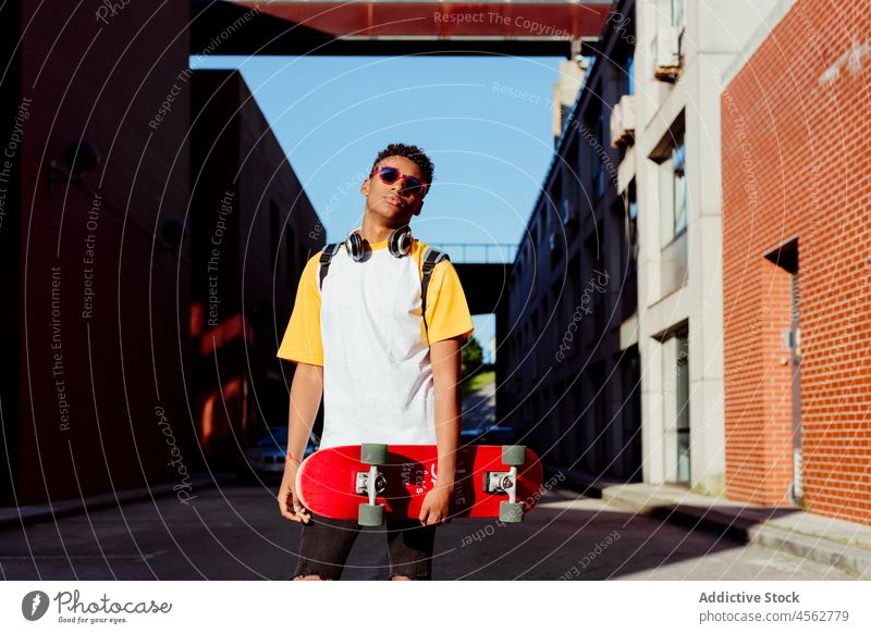 Young black man with skateboard on the street student school teenager daylight horizontal city leisure lifestyle male boy sunglasses attractive fun brick