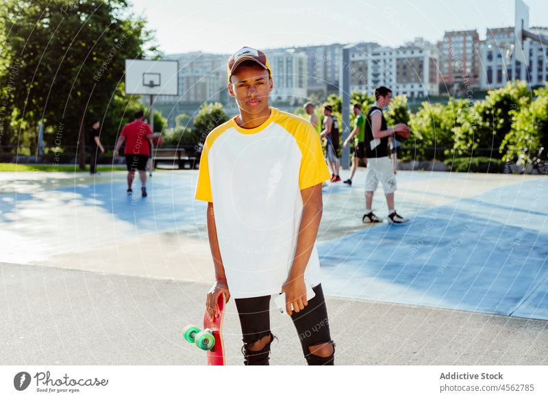 Young black man with t-shirt and cap posing at park young male boy concentrated street portrait urban city skateboard handsome lifestyle teenager mixed race sun