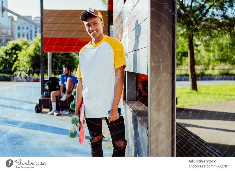 Young black man with t-shirt and cap posing at park young male boy happy smile phone street portrait urban city skateboard handsome attractive colorful