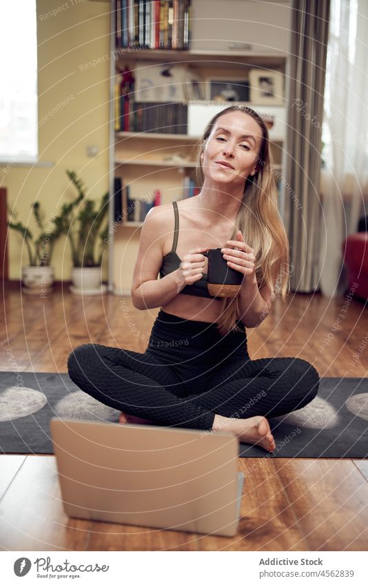 Positive woman with hot drink near laptop during yoga session training healthy lifestyle wellness tutorial lesson online cup beverage coffee positive glad