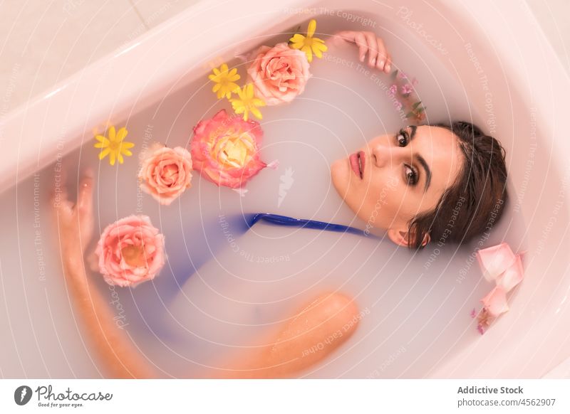 Young woman lying in milk bath with flowers relax model portrait swimwear spa wellness swimsuit blossom rest fresh bloom sensual procedure wellbeing skin care
