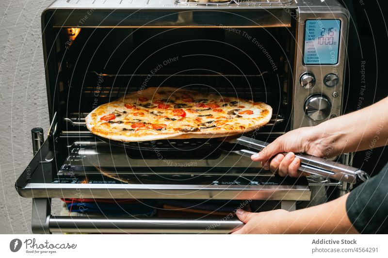 Crop woman taking cooked pizza from oven meal baked kitchen hot ready take delicious cheese tomato mushroom food prepare dish appetizing process ingredient