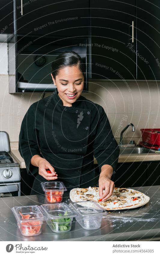 Smiling ethnic chef woman making pizza tomato cook kitchen professional add restaurant food prepare job culinary cuisine occupation uniform process fresh staff