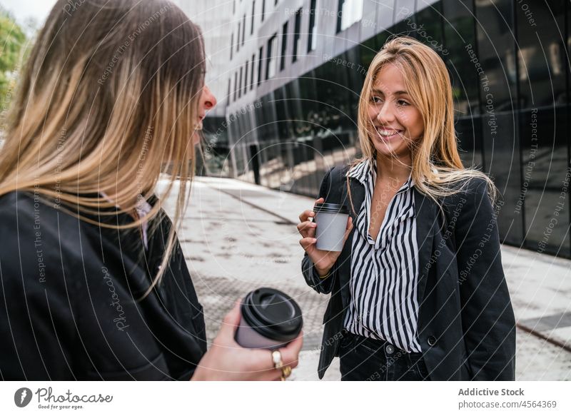 Cheerful businesswomen with takeaway coffee on street pathway walkway spend time urban coworker hot drink to go beverage paper cup colleague positive female