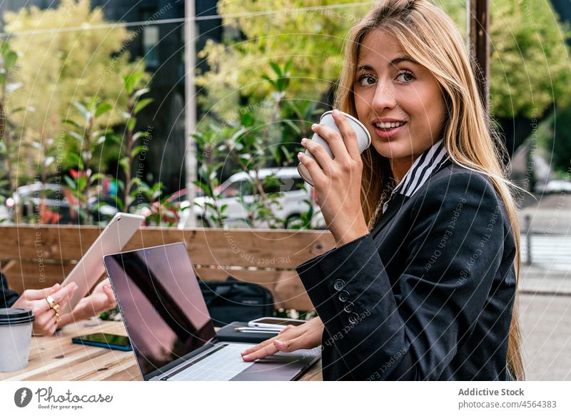 Businesswoman with coffee at table with laptop in cafe businesswoman terrace online browsing work hot drink modern street spend time city device gadget