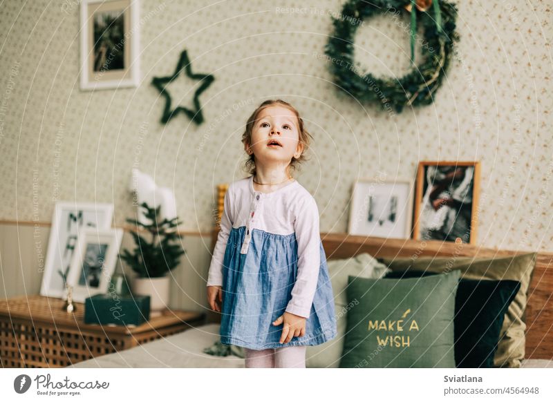 A happy girl is playing on the bed on Christmas morning in a room decorated for Christmas or New Year. Childhood, festive morning, Christmas mood christmas
