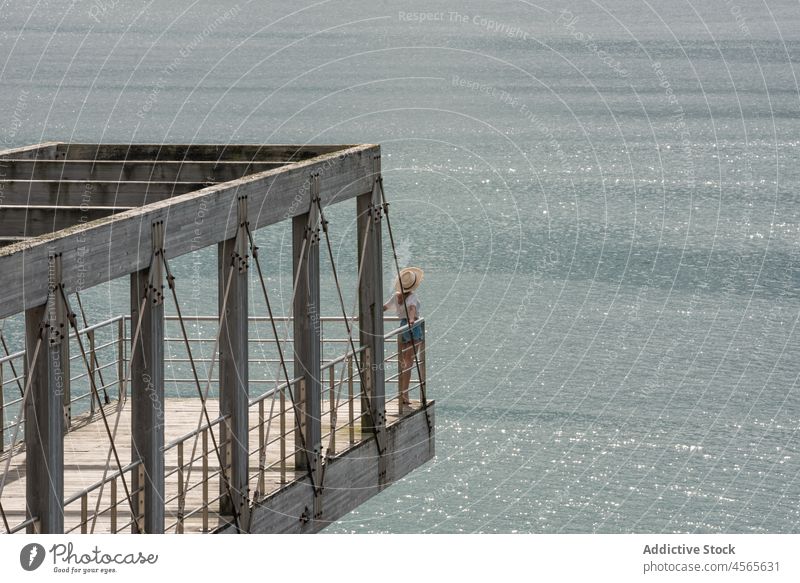 Woman sitting on pier against calm sea woman tourist travel observe wooden seascape boardwalk fence construction railing cargadero da insua spain female galicia