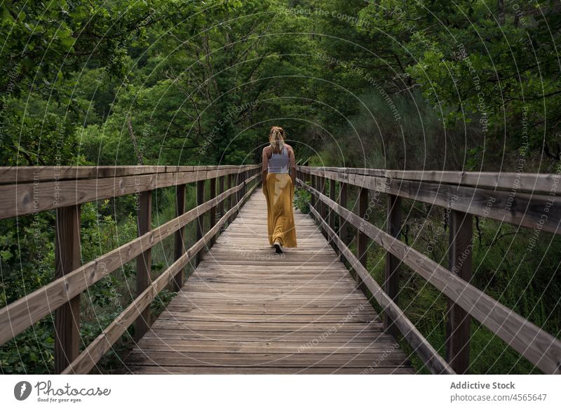 Young woman standing on wooden footbridge in green mountainous valley river mao galicia sacra spain traveler nature tourism tourist explore trip adventure