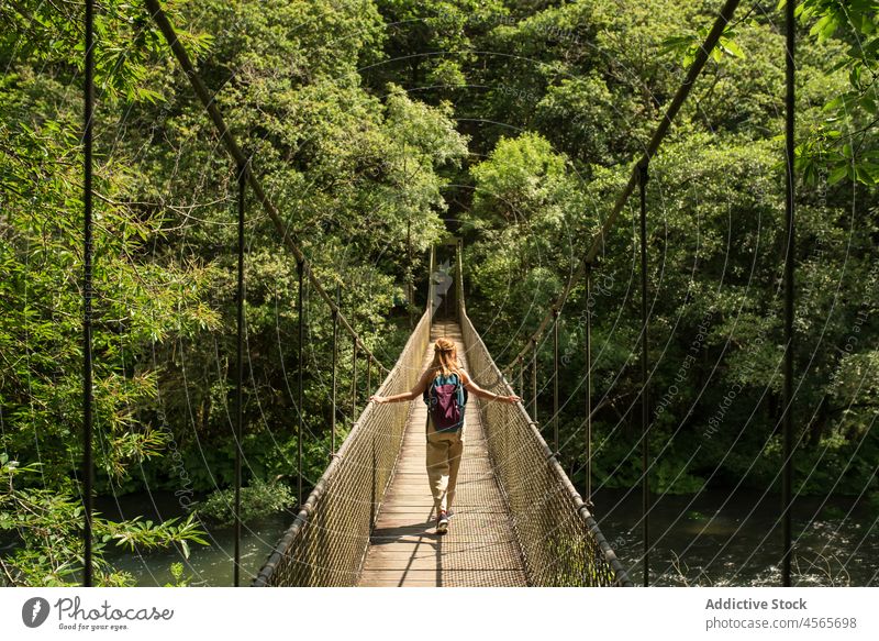 Anonymous woman walking on footbridge in forest in national park spain suspension galicia fragas do eume woods nature tourist traveler explore location