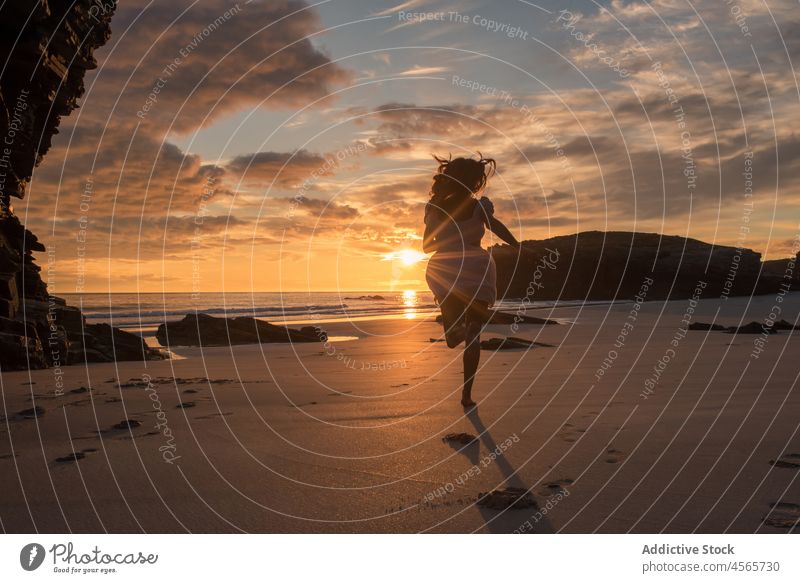 Unrecognizable woman running on beach at sunset silhouette jog sundown sea shore picturesque beach of the cathedrals galicia spain enjoy female seascape coast