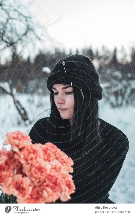 Birthday in winter flowers girl portrait Black hair black hat Pink carnations girl holding flowers young woman Winter cold blurred background daylight