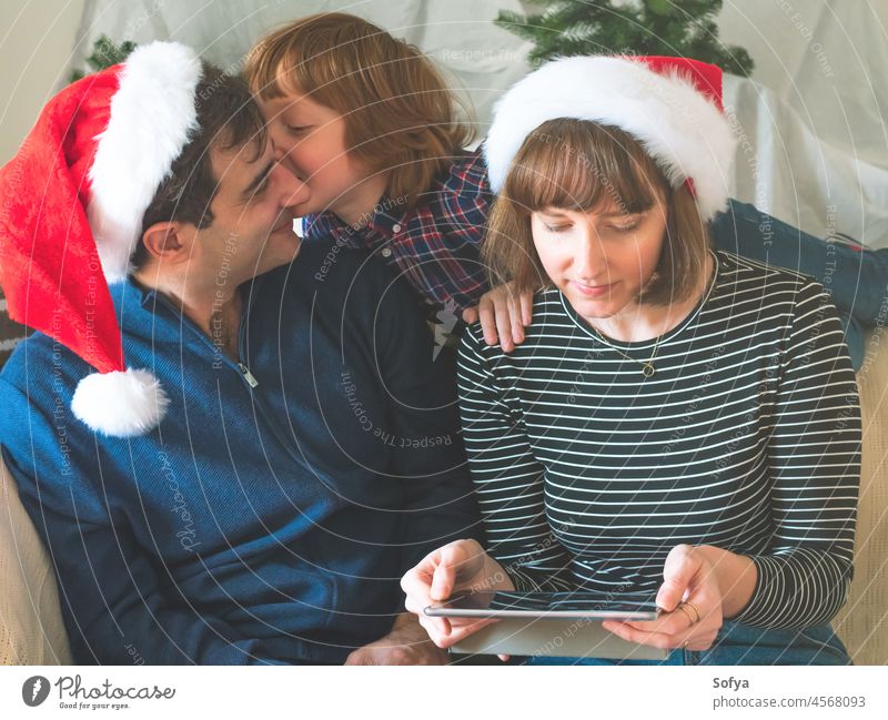 Mother, dad and son in santa caps on christmas holidays father mother enjoy love tablet december gadget lifestyle online smile kid new year winter family