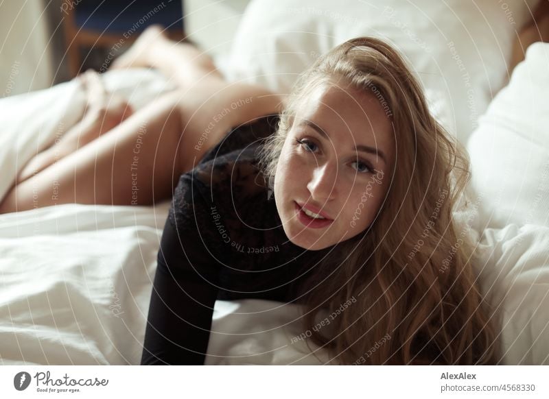 Portrait of young blonde long haired woman lying in bed looking at camera Youthfulness salubriously Facial expression Warmth inside Lifestyle Long-haired senses