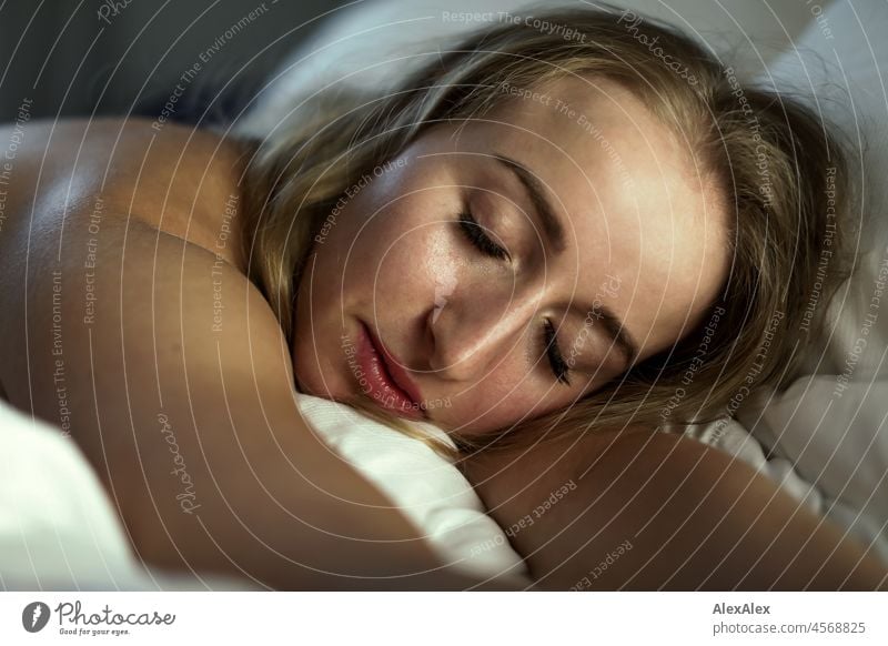 Nude portrait of a young, blond, long-haired woman apparently asleep in bed on her stomach Youthfulness salubriously Facial expression Warmth inside Lifestyle