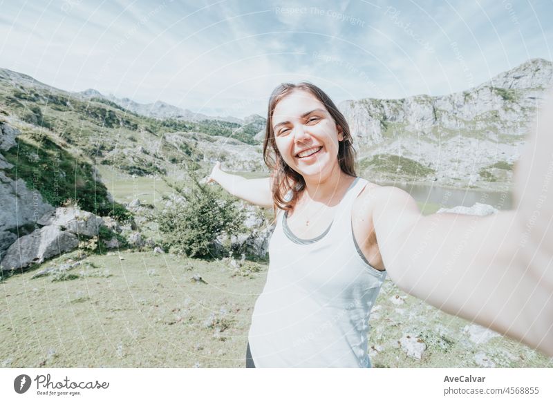 Young woman taking a selfie on the mountains after a travel day. Idyllic scenario views of the spanish mountains celebrating life. Resting after a day of walking copy space for add