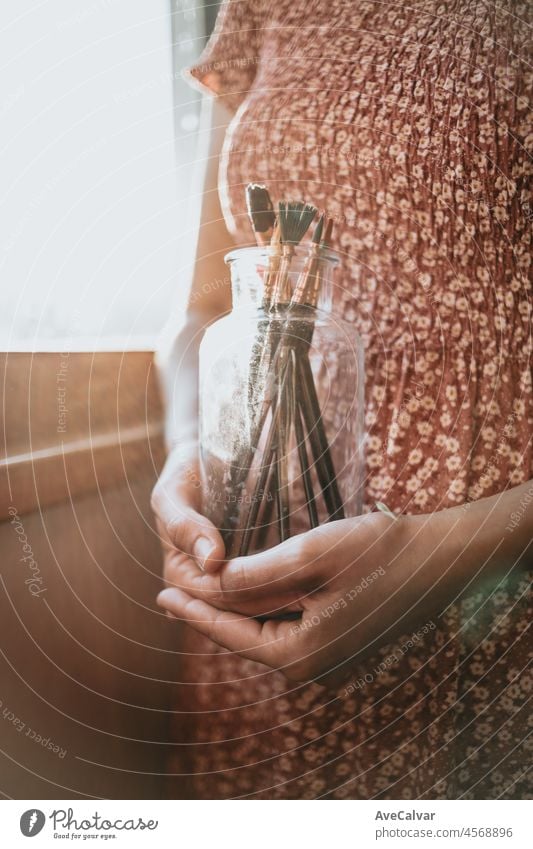 Young woman artist hands grabbing a bottle filled with paint pencils and brushes, ready for painting acrylic. Artistic concepts, artist concept. Beauty dress concept vintage with sun bean, copy space