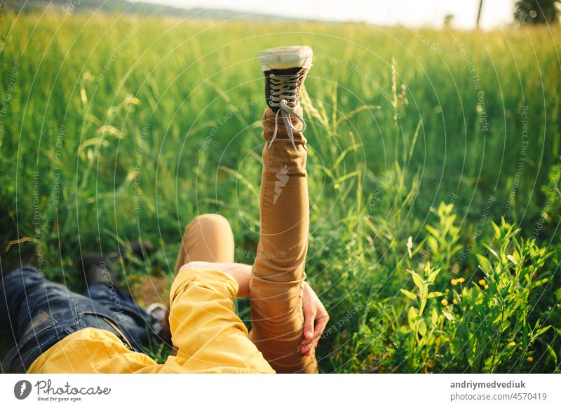 woman and man having fun outdoors. Loving hipster couple walking in the field, kissing and holding hands, hugging, lying in the grass and lifting their legs up in the summer at sunset. valentines day