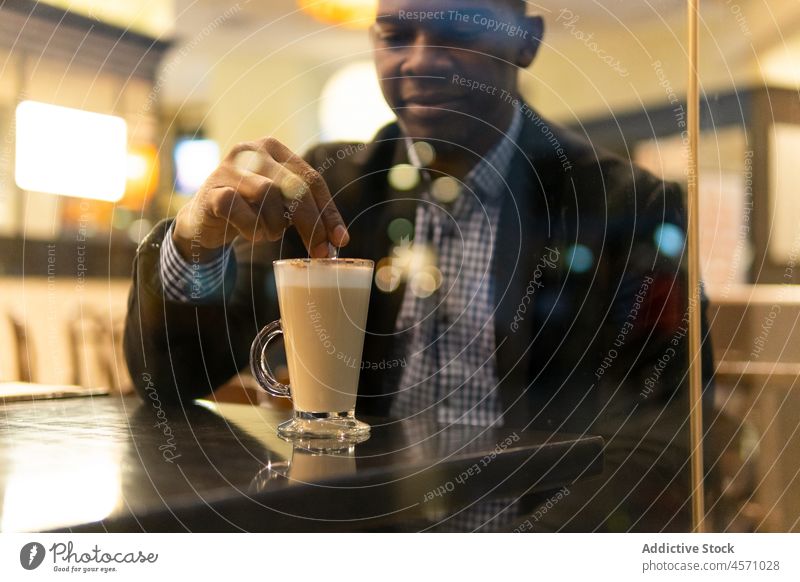 Crop black man stirring latte macchiato in cafeteria mocha coffee smile elegant drink window coffee break hot drink businessman male young african american